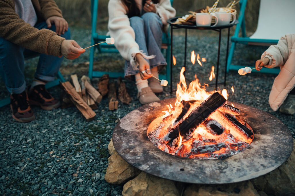 Happy family roasting marshmallow sitting by the fire outdoors