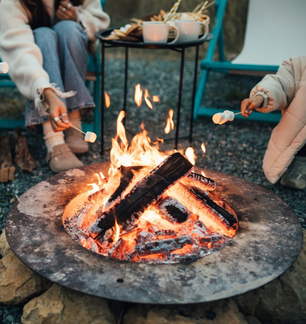 Happy family roasting marshmallow sitting by the fire outdoors.