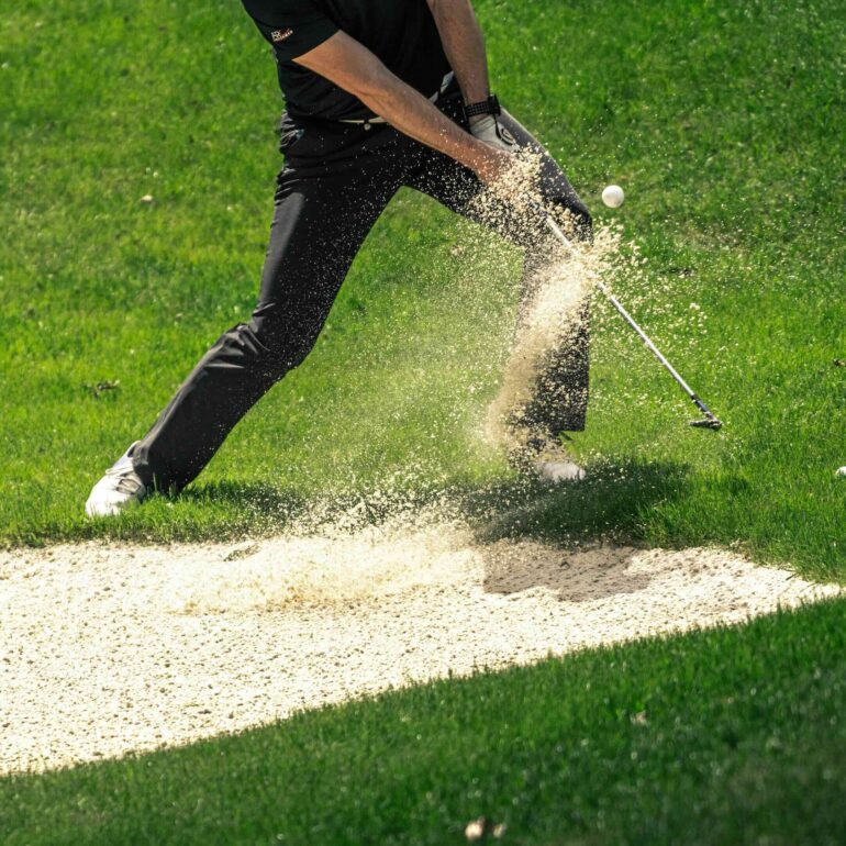 Golfer swinging from a sand trap
